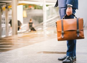 Closeup Of A Businessman Holding leather Briefcase Going To Work after rain